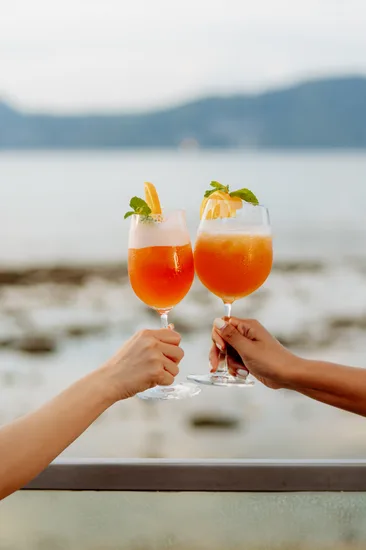 Two Aperol spritz cocktails toasted over the sea at La Gritta